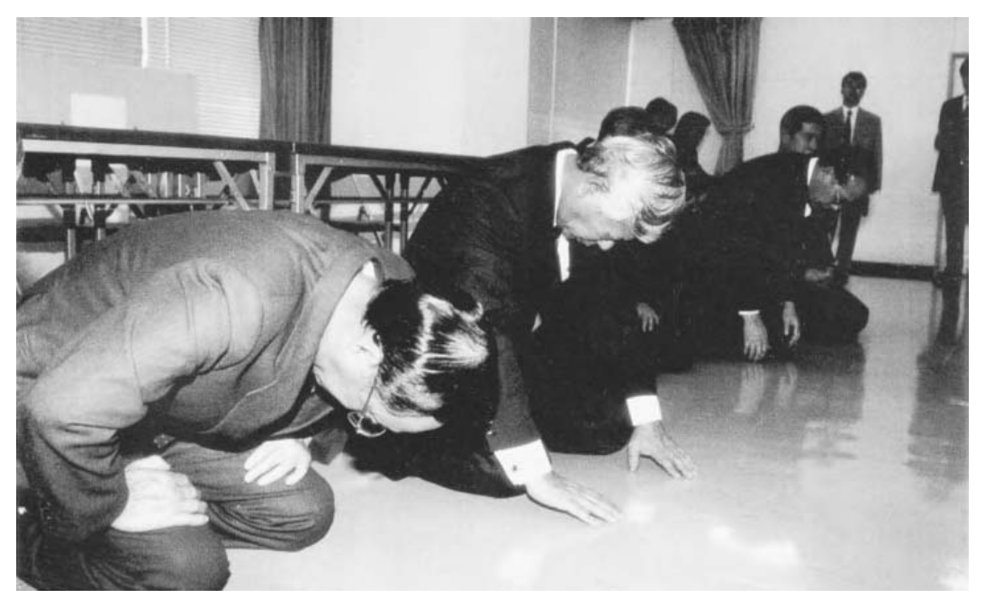 1996年3月，在最初诉讼提起七年后，向原告提供含有HIV的未加热血液制品的绿十字公司及另外三名被告，终于与受害者达成和解。图中，绿十字公司社长及董事们向原告下跪叩首致歉。90年代这一系列丑闻，不仅动摇了社会对商界与政界的信任，也重创了人们对负责监管产业、原本通常享有较高声望的官僚体系的信心。照片由《每日新闻》提供。